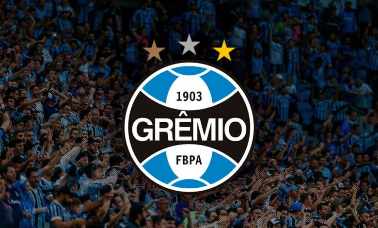 Escudo do Grêmio com torcedores ao fundo